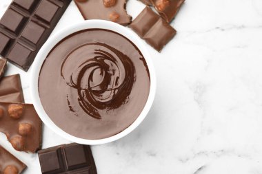 Erimiş çikolatalı kase ve beyaz mermer masa üzerinde parçalar, düz. Metin için boşluk