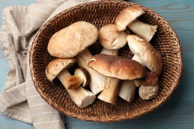 Hasır sepetin içinde taze porcini mantarları açık mavi ahşap masa, üst manzara