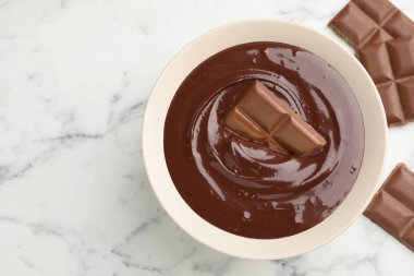 Erimiş çikolata ve parçalar beyaz mermer masada, düz yerde. Metin için boşluk