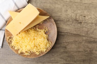 Ahşap masanın üstünde rendelenmiş ve peynir parçaları, üst manzara. Metin için boşluk