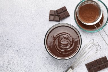 Erimiş çikolata kasede, parçalarda, kakao tozunda ve açık gri masada çırpılmış, düz bir şekilde. Metin için boşluk