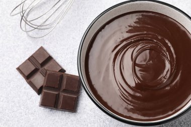 Erimiş çikolata kasede, parçalanmış ve çırpılmış açık gri masa, düz uzanmış