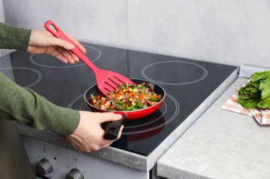 Kızartma tavasında taze sebze ve spatula karıştıran kadın, yakın plan.