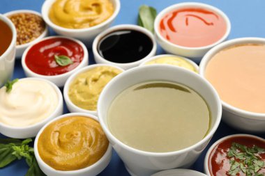 Mavi arka planda farklı soslar ve otlar, yakın plan.