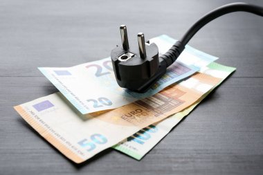 Siyah ahşap masanın üzerinde euro banknotları olan elektrik teli, yakın plan.