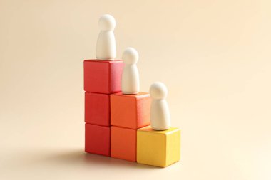 Kazandım. Küp üzerinde insan figürleri, bej arka planda tahta figürler, yakın plan.