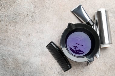 Tabaktaki saç boyama ürünü ve açık gri masada farklı kuaför aletleri, düz yatak. Metin için boşluk