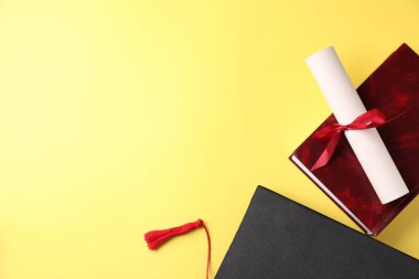 Diploma, mezuniyet şapkası ve sarı arka plan kitabı. Metin için boşluk