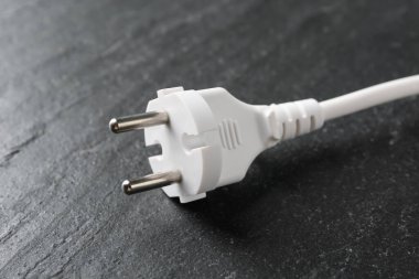 Siyah masa üzerinde fişi olan elektrik kablosu, yakın plan.