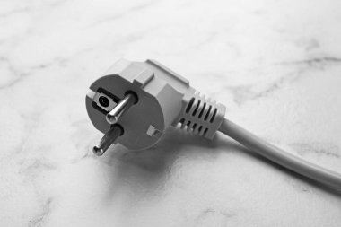 Beyaz mermer masa üzerinde fişi olan elektrik teli, yakın plan.