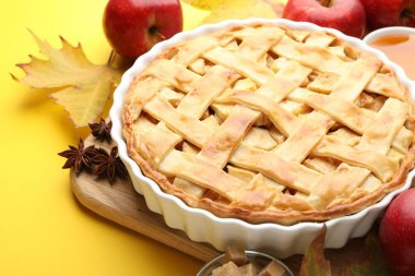 Lezzetli ev yapımı elmalı turta ve sarı arka planda malzemeler, yakın plan.