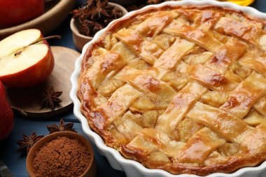 Lezzetli ev yapımı elmalı turta ve mavi ahşap masada malzemeler, yakın plan.