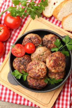 Maydanozlu leziz köfteler, domatesler ve ahşap masada ekmek.