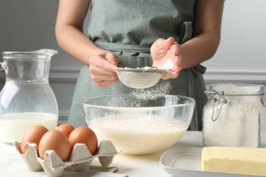 Hamur yapmak (sıvı hamur). Beyaz masada un yiyen bir kadın. Kapalı alanda, yakın plan.