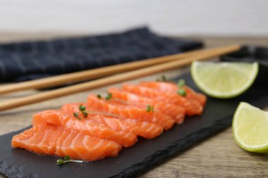 Mikroyeşillikli taze somon balığı ve ahşap masada yeşil arka planda limon, yakın plan.