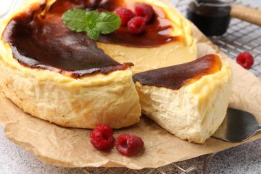 Ahududulu Lezzetli Bask peynirli kek ve açık gri desenli masa üzerinde nane şekeri, yakın plan.