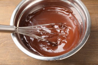 Erimiş çikolata ve çırpılmış kase içinde ahşap masada, yakın plan.