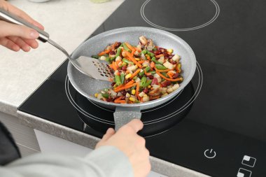 Kızartma tavasında taze sebze ve spatula karıştıran kadın, yakın plan.