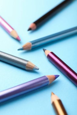 Açık mavi arkaplanda göz kalemleri, yakın plan.