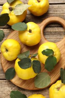 Tahta masadaki yapraklarla taze, olgun ayvalar.