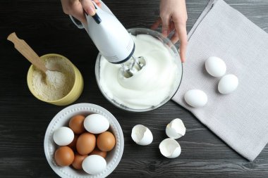 Siyah ahşap masada yumurta beyazı çırpan bir kadın.