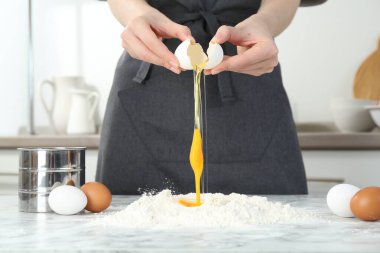 Mutfaktaki beyaz mermer masada yumurta kıran kadın, yakın plan.