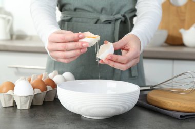 Mutfaktaki gri masada yumurta kıran kadın, yakın plan.