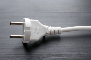 Siyah ahşap masada fişi olan elektrik kablosu, yakın plan.