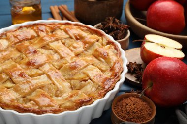 Lezzetli ev yapımı elmalı turta ve mavi ahşap masada malzemeler, yakın plan.