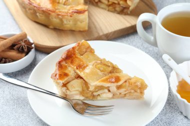 Lezzetli ev yapımı elmalı turta, baharat ve çay. Gri desenli masa, yakın plan.