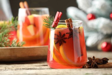 Lezzetli punç bardaklar, baharatlar ve Noel dekorları ahşap masada, yakın plan.