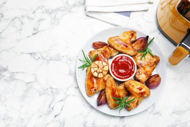 Beyaz mermer masada soslu ızgara tavuk kanadı, baharat ve hava fritözü düz yerde. Metin için boşluk