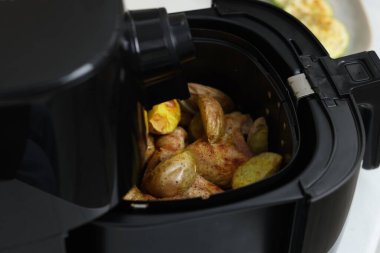 Kızarmış tavuk kanatları ve patates dilimleri ile servis sepeti, yakın plan.