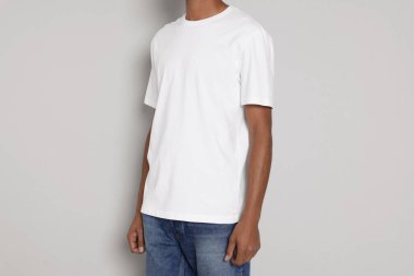 Man wearing white t-shirt on light grey background, closeup. Mockup for design