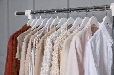 Gri duvarın yanında asılı farklı giysiler, yakın plan.