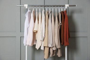 Gri duvarın yanında asılı farklı elbiseler.