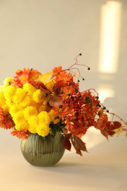 Sonbahar atmosferi. Güzel çiçekli vazo ve bej arka planda böğürtlen, yakın plan.