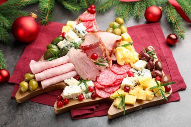 Lezzetli Noel Şarküteri tahtası. Atıştırmalıkları, köknar dalları ve gri desenli masalarda takılar.