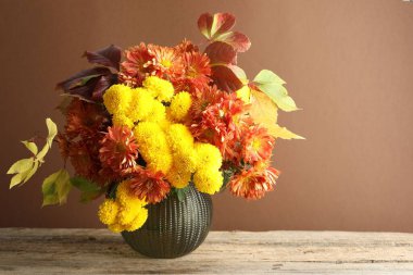 Sonbahar atmosferi. Güzel çiçekli vazo ve ahşap masa üzerinde kahverengi arkaplan, metin için boşluk