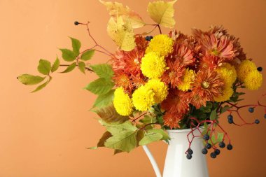 Sonbahar atmosferi. Güzel çiçekli vazo ve turuncu arka planda böğürtlen, yakın plan.