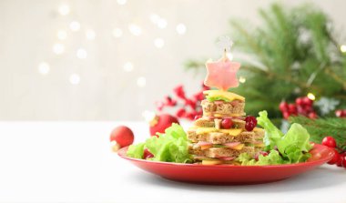 Noel yemeği. Ekmek, peynir, jambon, marul ve dekordan yapılmış fidan ağacı arka planda bulanık ışıklarla, yazı için yer açarak beyaz masanın üzerinde duruyor. Bokeh etkisi