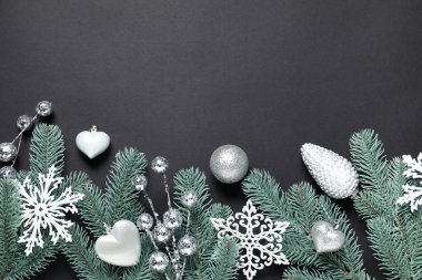 Köknar ağacı dalları ve siyah arka planda Noel dekoru olan düz bir kompozisyon. Metin için boşluk