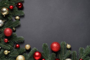 Köknar ağacı dalları ve siyah arka planda Noel dekoru olan düz bir kompozisyon. Metin için boşluk