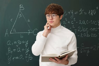 Okula dönelim. Matematik ödevi olan bir öğrenci karatahtanın yanında kitap tutuyor.