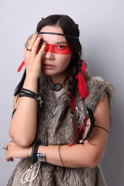 Yüzü açık gri arka planda olan şaman kadın.