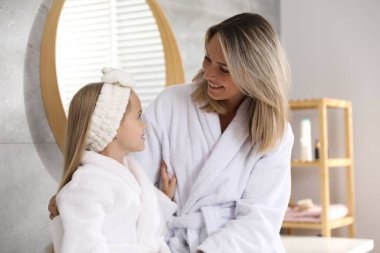 Banyoda bornozlu mutlu anne ve kız.