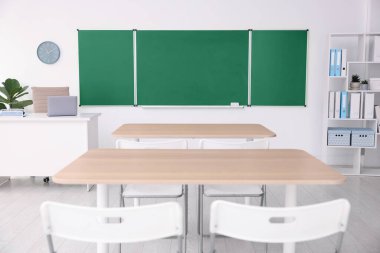 Sınıfta yeşil karatahta, masalar ve sandalyeler var. Tasarım için model