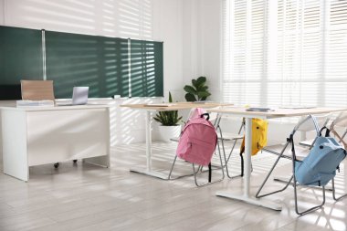 Sınıfta yeşil karatahta, sıralar ve sandalyeler.