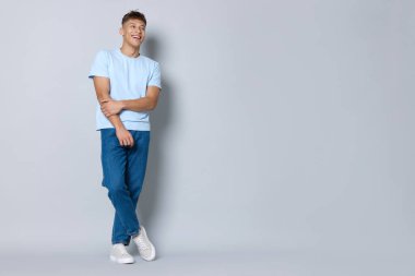 Açık gri arka planda şık kotlu yakışıklı genç adam, mesaj için yer