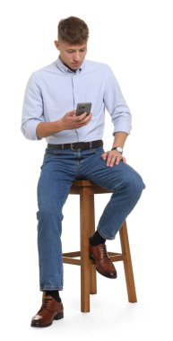 Beyaz arka planda akıllı telefon kullanan şık kotlu yakışıklı bir genç.